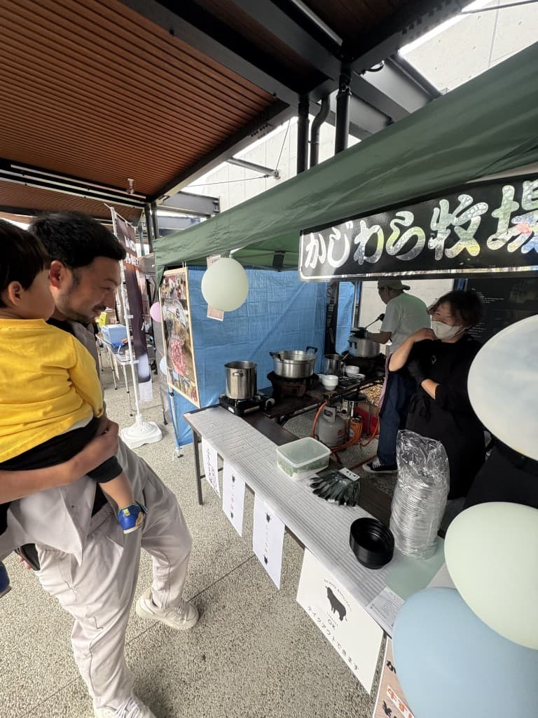 屋外イベントのかじわら牧場ブースで調理・配膳をするスタッフと来場者
